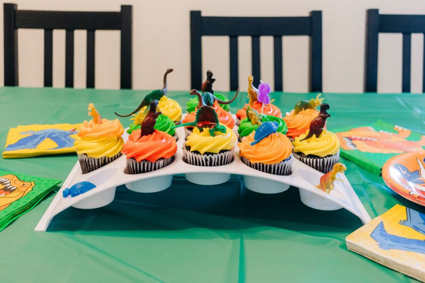 Cupcakes with dinosaur decorations and a 2 candle