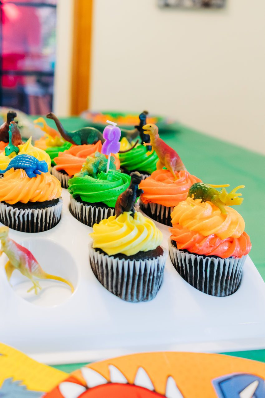 Cupcakes with dinosaur decorations and a 2 candle