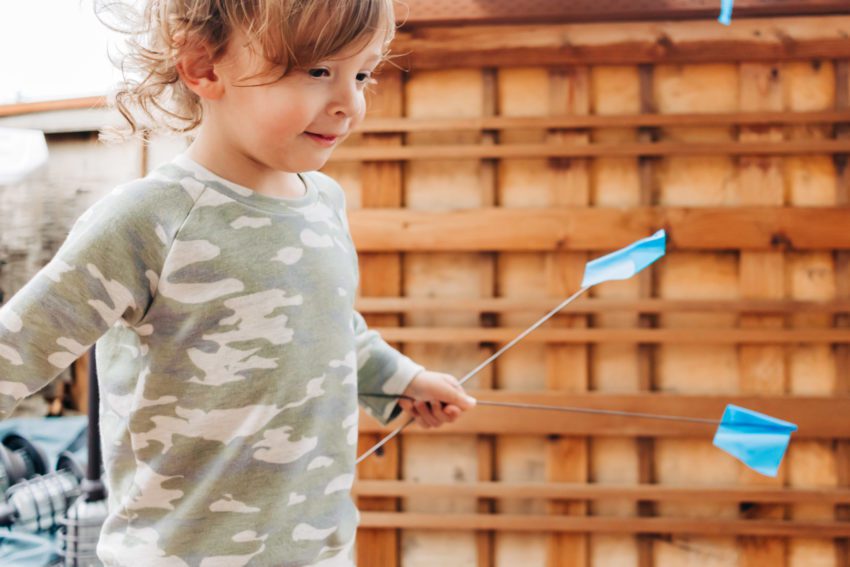 Toddler with a camouflage raglan sweater and little blue flags