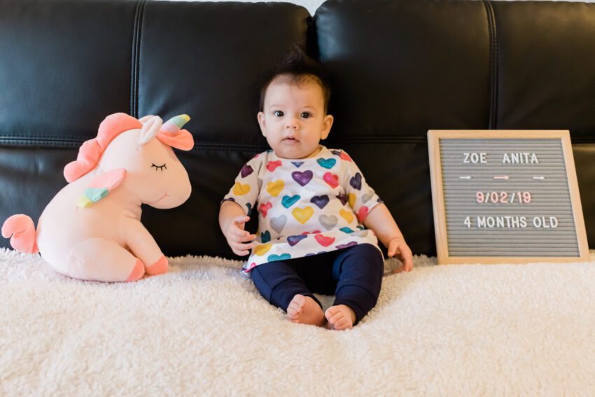 4 month old in colorful heart dress and blue pants