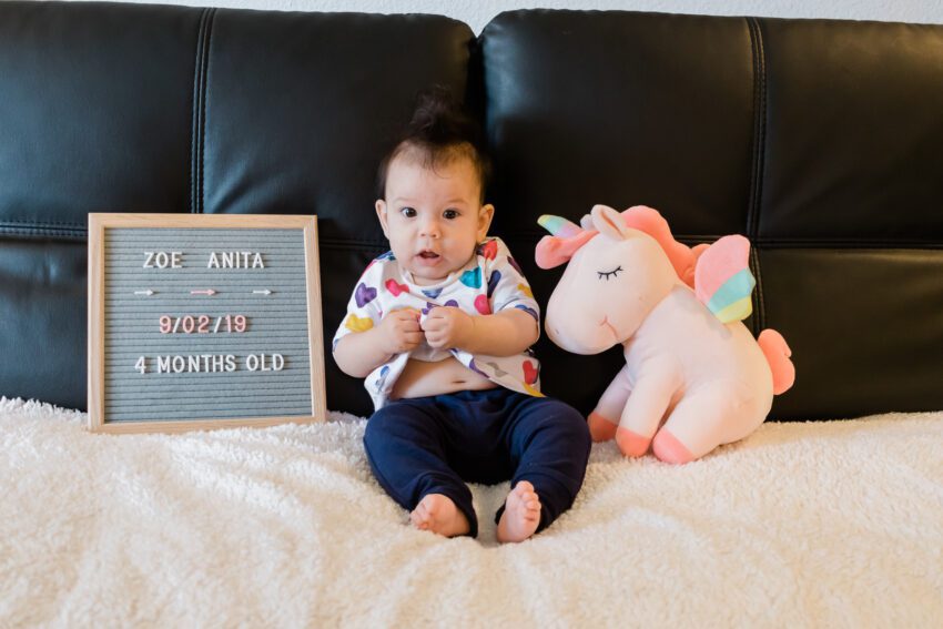 4 month old in colorful heart dress and blue pants
