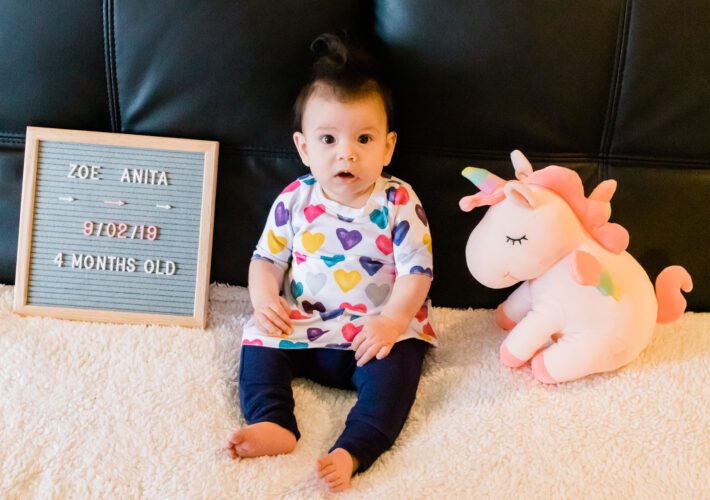 4 month old in colorful heart dress and blue pants
