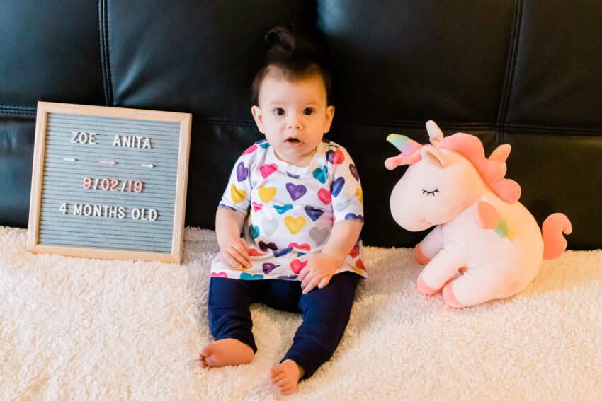 4 month old in colorful heart dress and blue pants