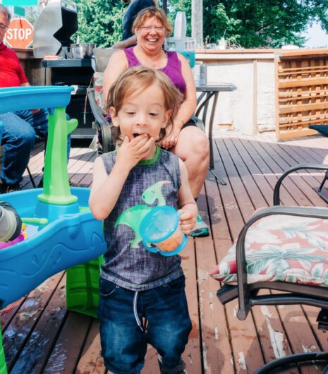 A toddler in a dinosaur tank top eating crackers