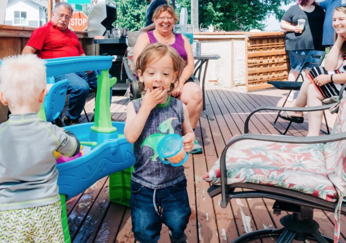 A toddler in a dinosaur tank top eating crackers