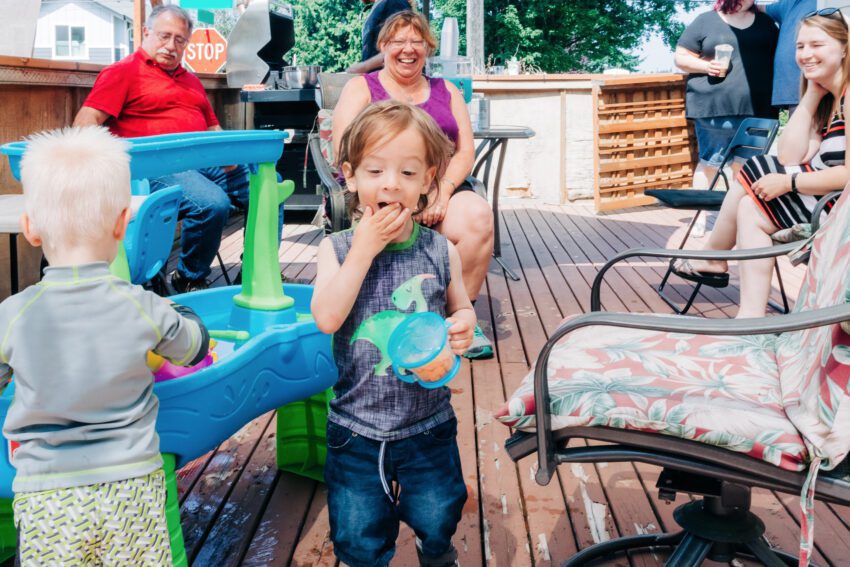 A toddler in a dinosaur tank top eating crackers